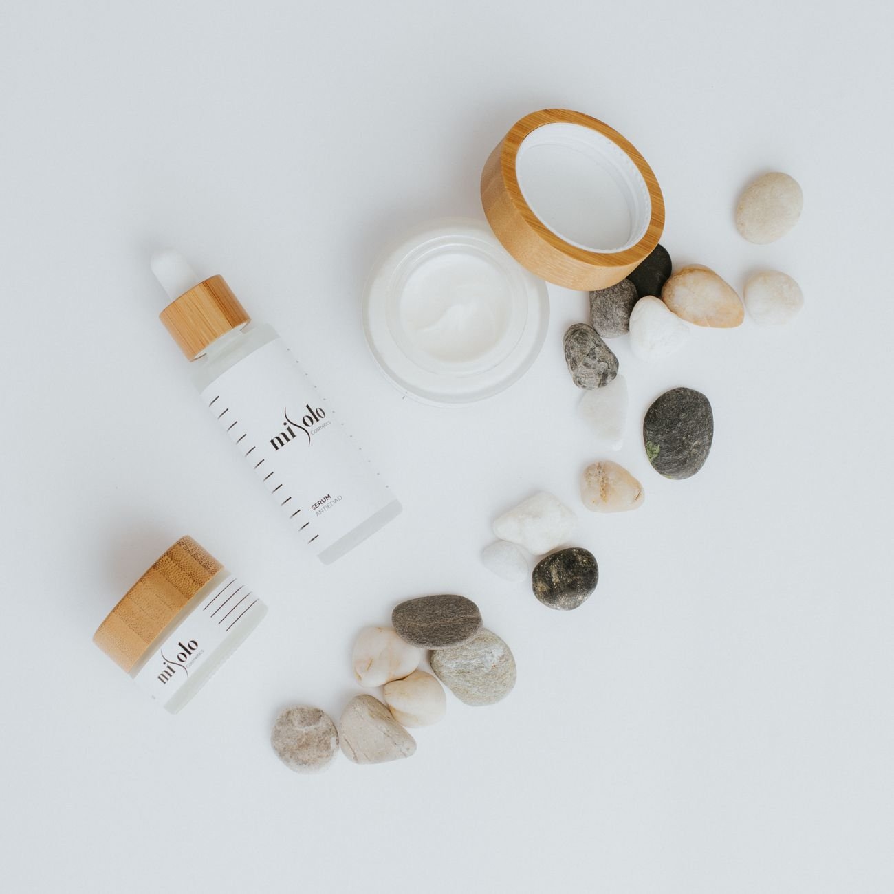 Flat lay of high-end skincare beauty products on a warm cream background.